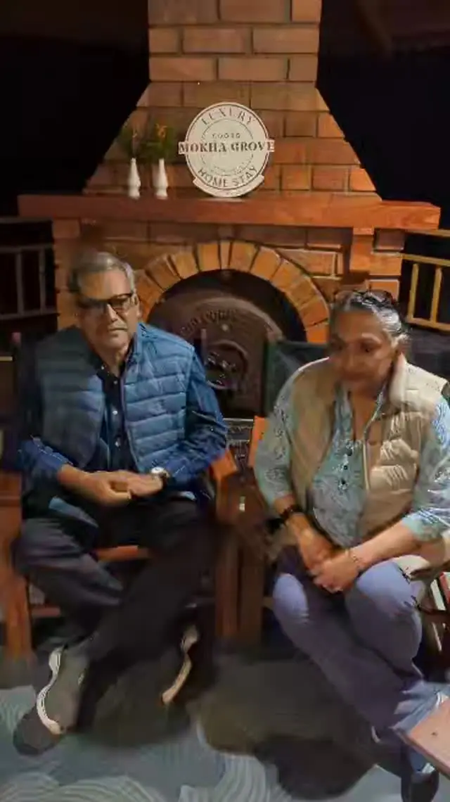 An older couple seated by the brick fireplace under the Mokha Grove sign at night