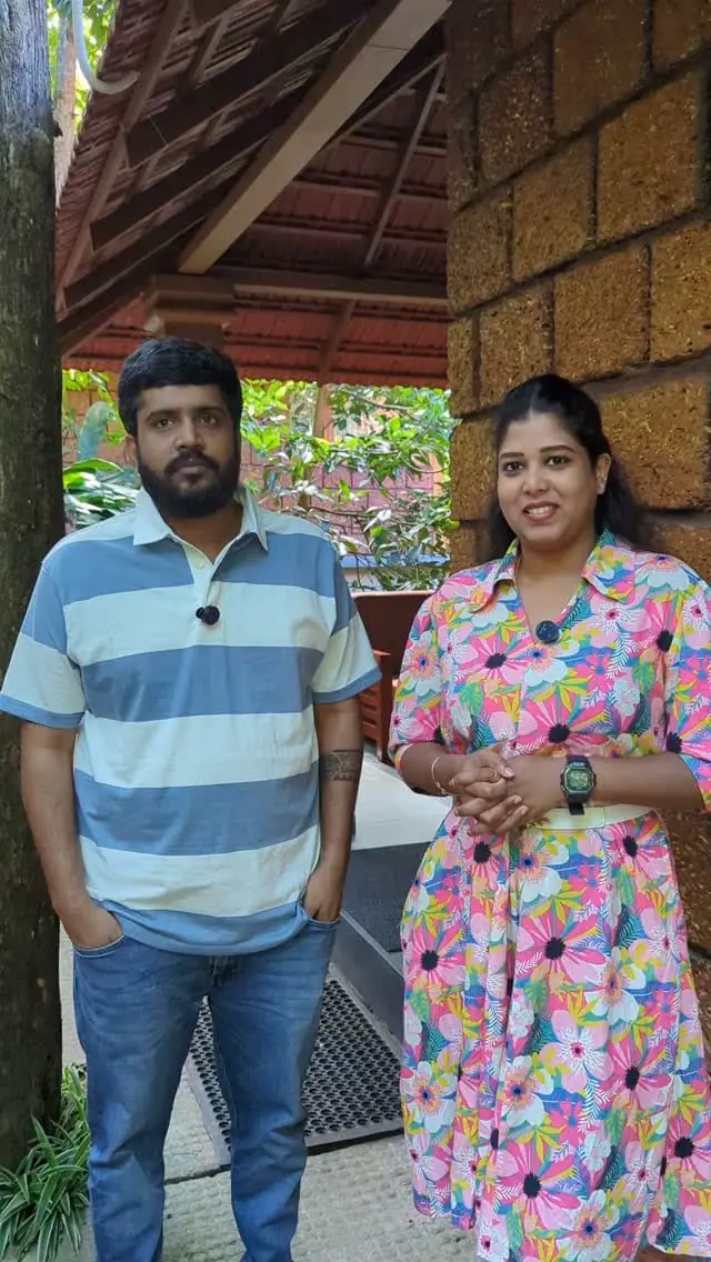 Two guests standing by a laterite stone wall and a tiled gazebo at Mokha Grove