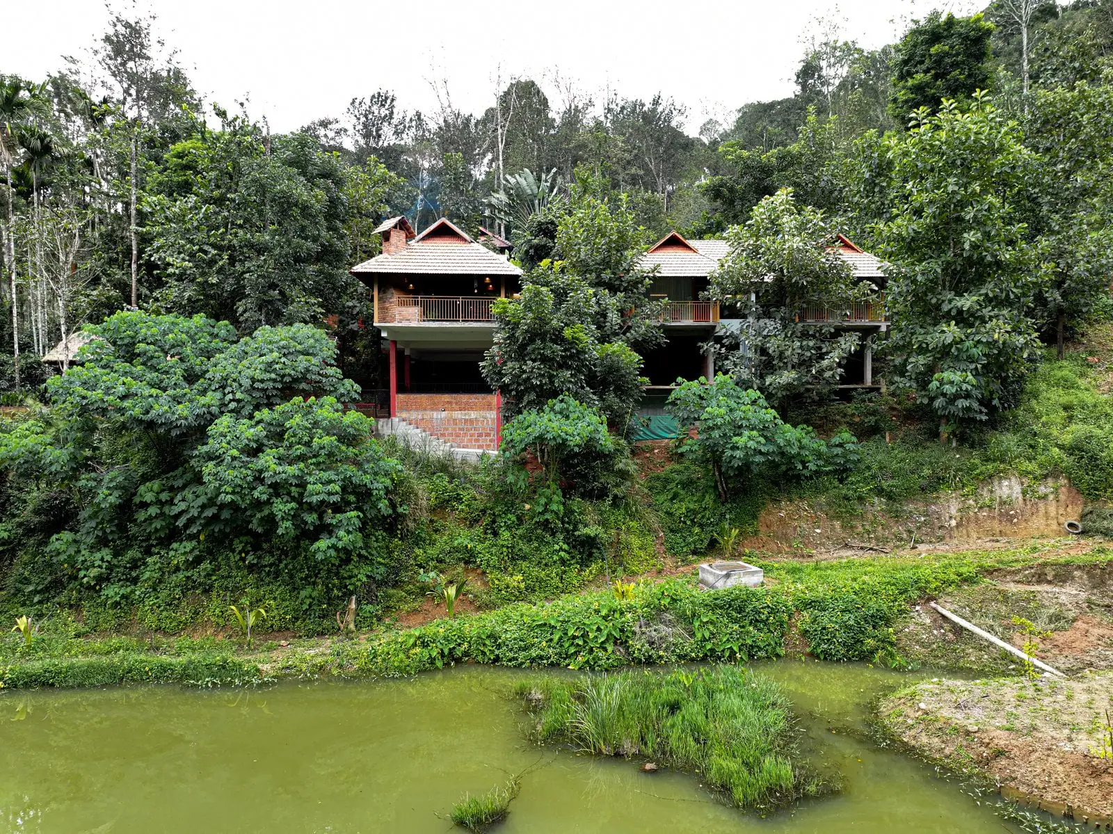 Drone view of two cottages on stilts above the estate pond