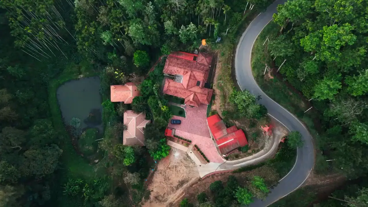 Top-down drone view of the estate road winding past the clay-tiled roofs