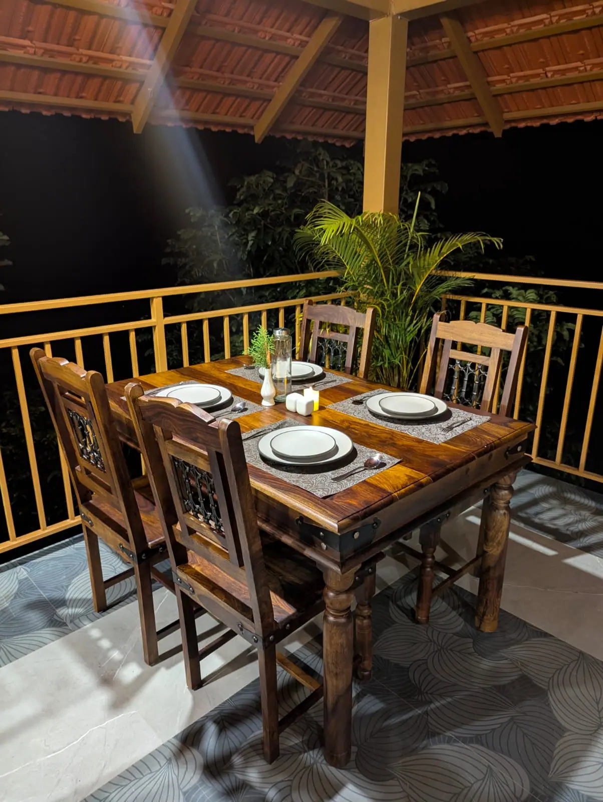 A timber table laid for two on a balcony among the trees