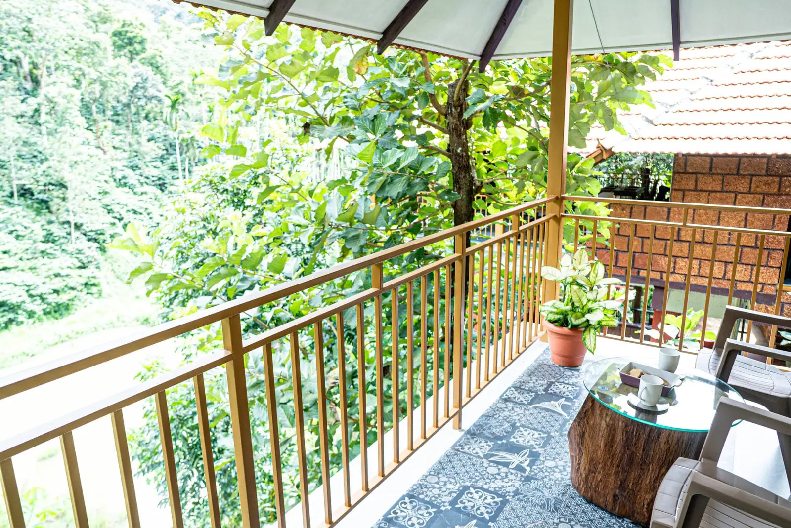 A private balcony with a tree-stump table and two chairs above the treetops of a coffee estate in Coorg