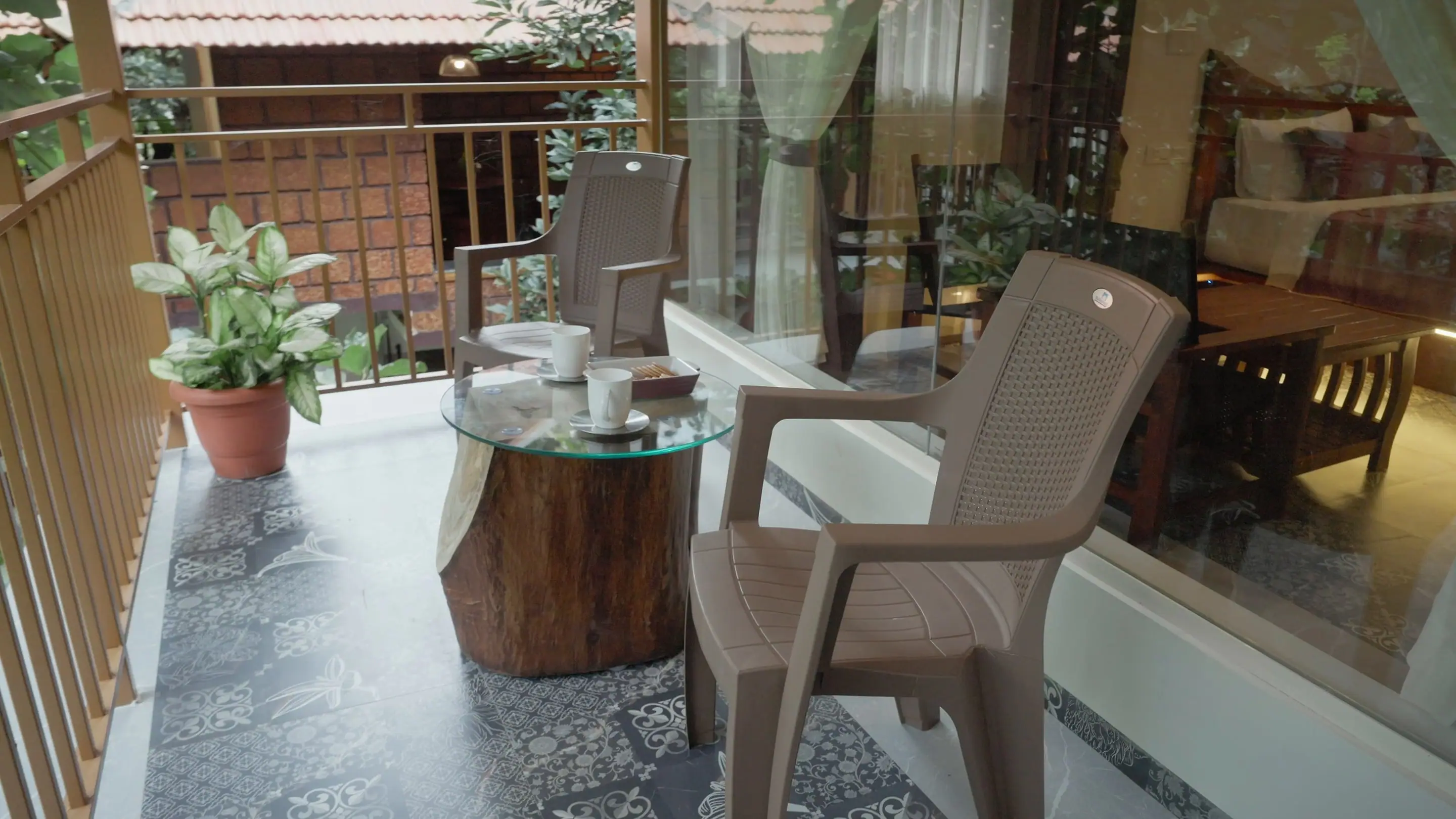 A balcony sit-out with a tree-stump table and chairs, the forest right outside