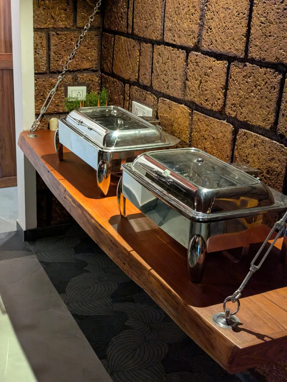 Breakfast kept warm in chafing dishes on a timber counter against a laterite wall