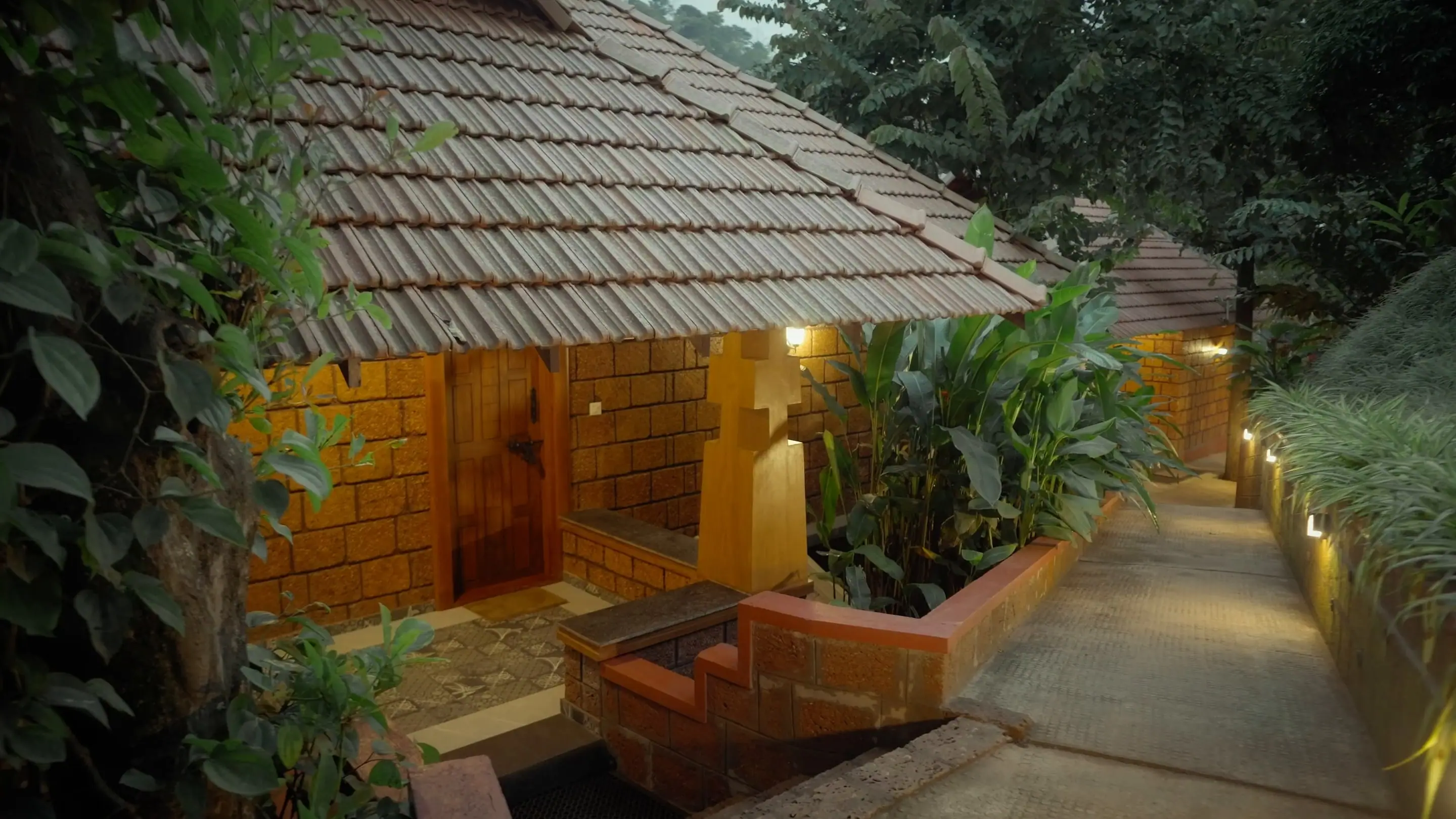 Lamp-lit laterite path between cottages at dusk on a coffee estate in South Coorg