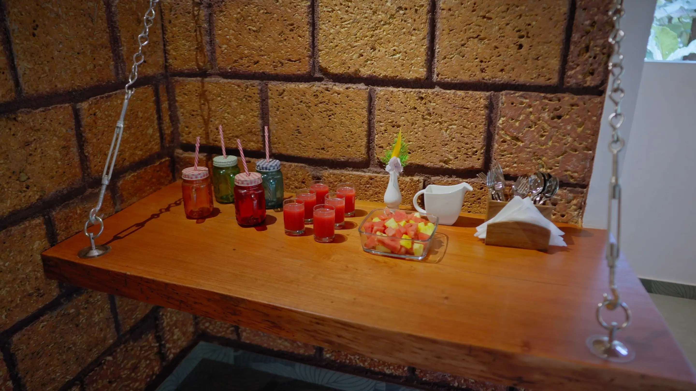 Glasses of fresh juice on a timber counter against a laterite wall