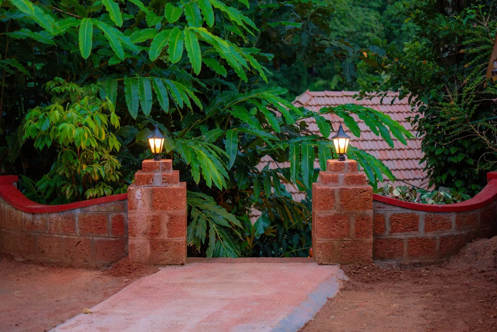 Lamp-lit laterite pillars at the entrance