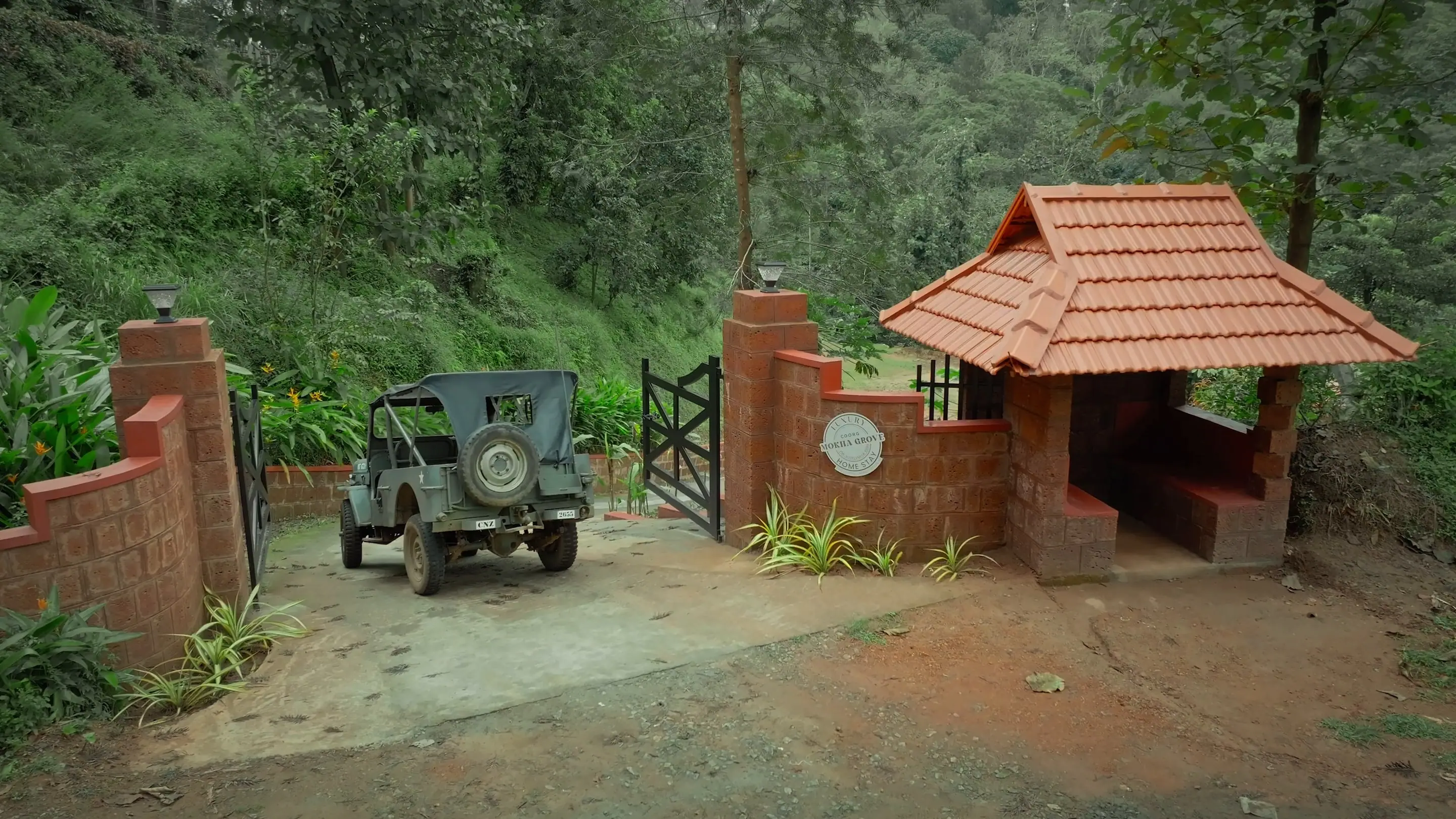 The open estate jeep parked at the gate by the laterite gatehouse, ready to set off