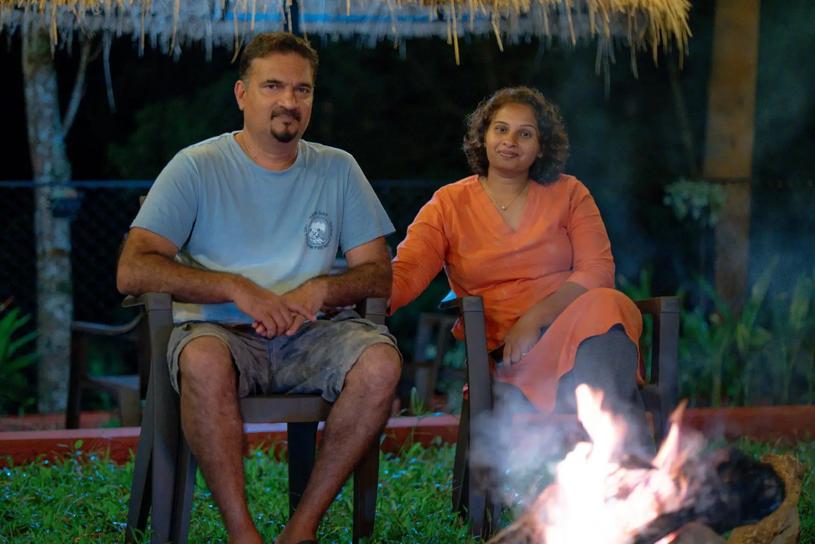 A couple seated by a bonfire at night