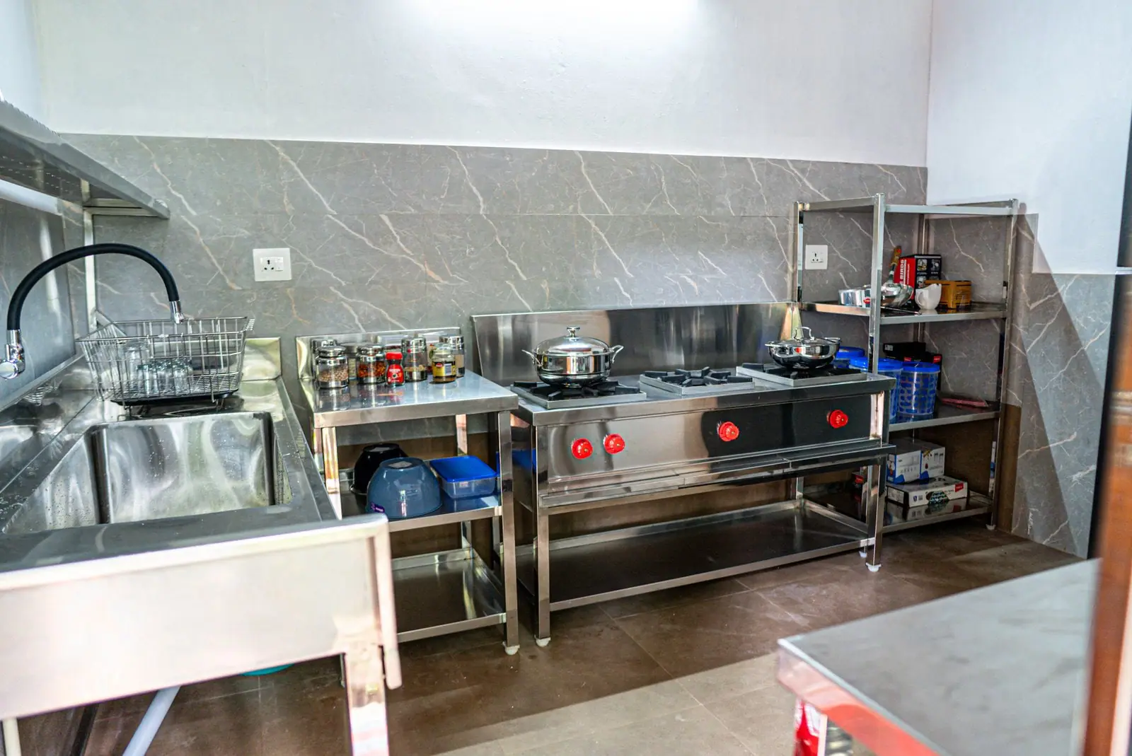 A clean steel kitchen with burners and racks