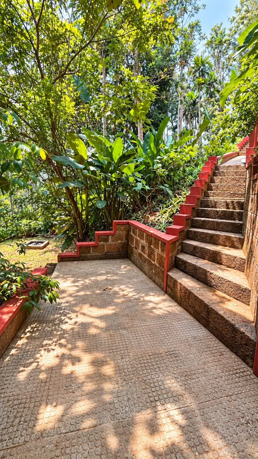 Laterite steps with red-painted edges climbing through garden planting on the estate