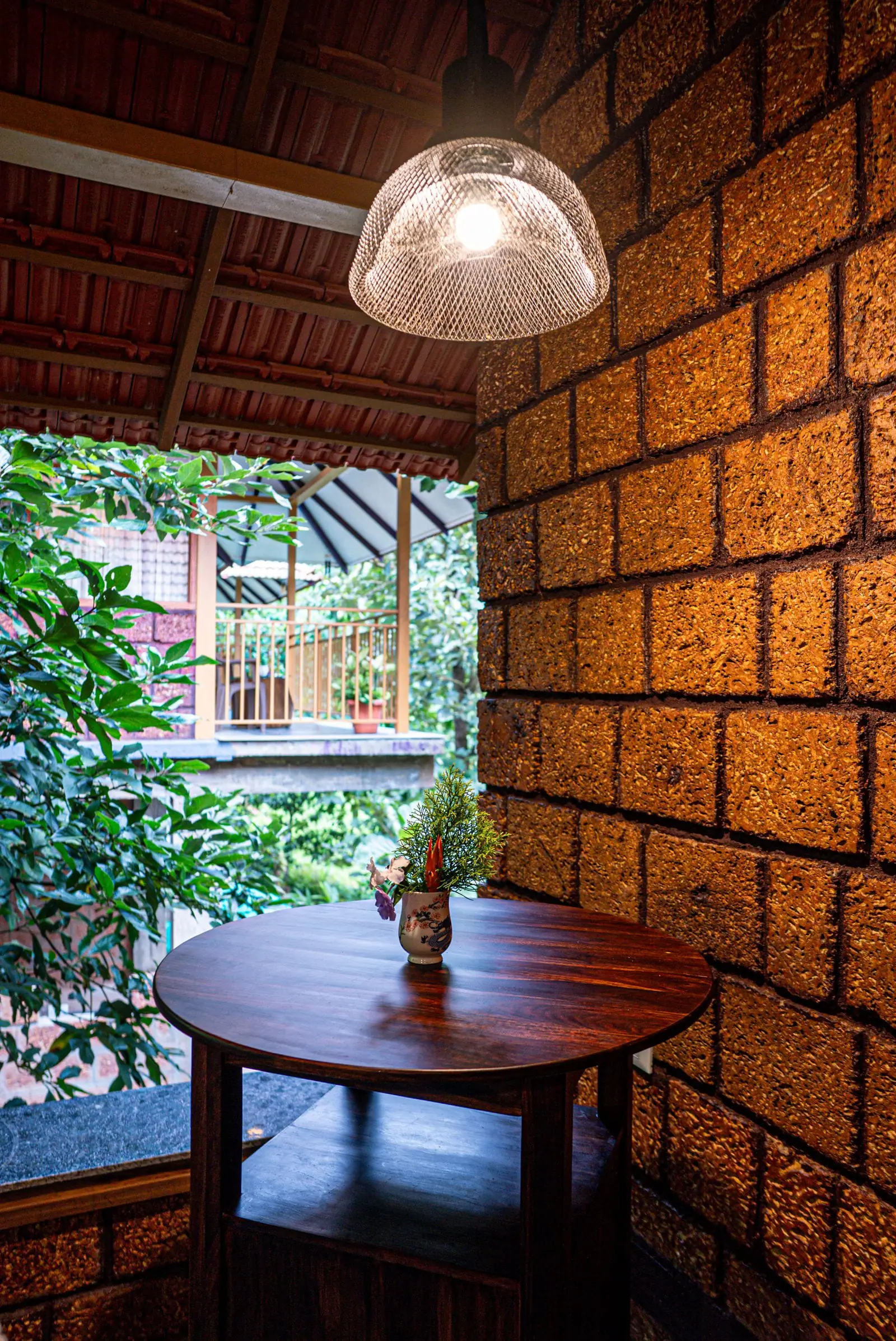 Stepped laterite walls and a lantern post among broad leaves and striped garden plants
