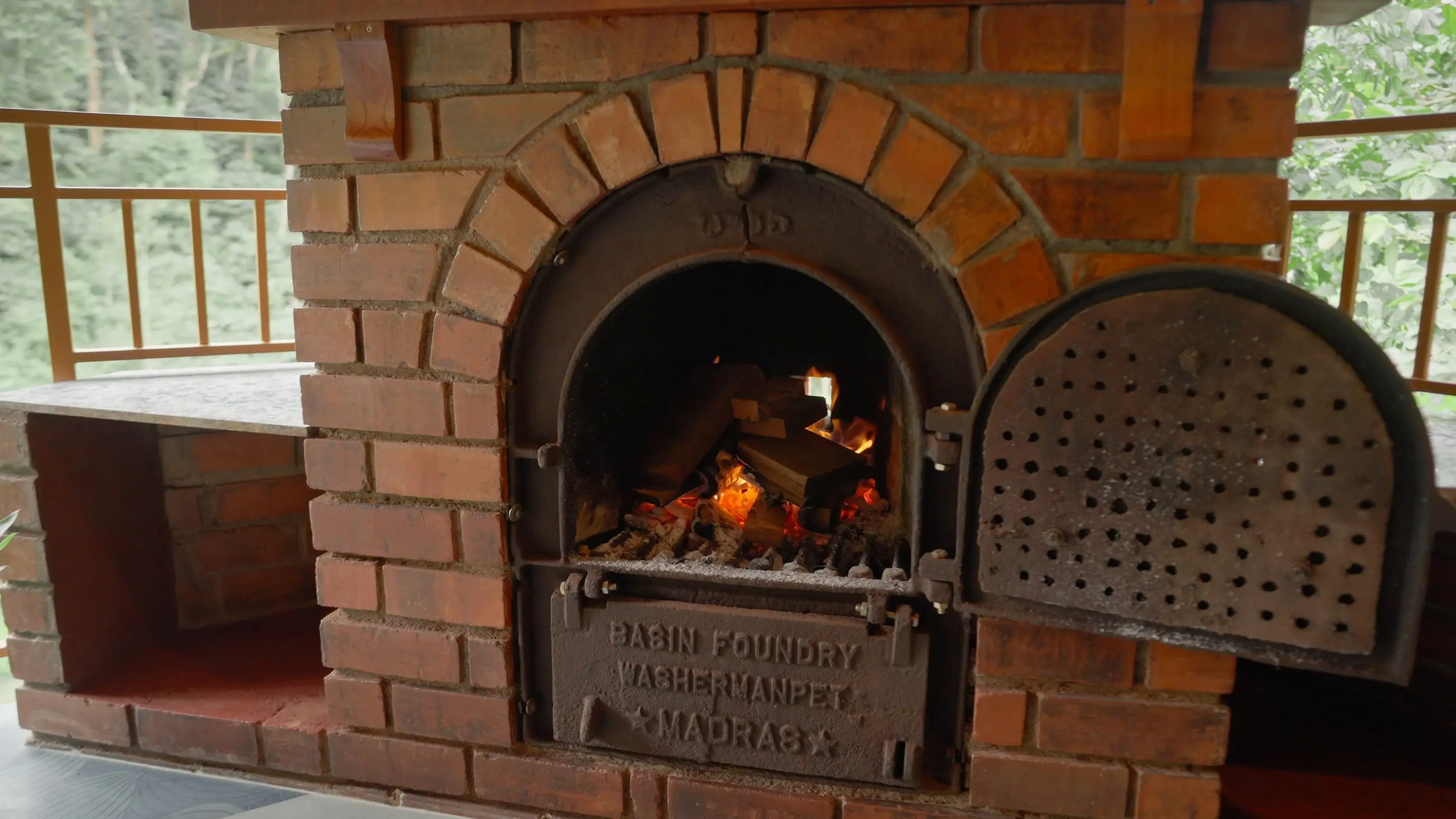 The pavilion's arched brick fireplace with a fire burning behind its iron doors