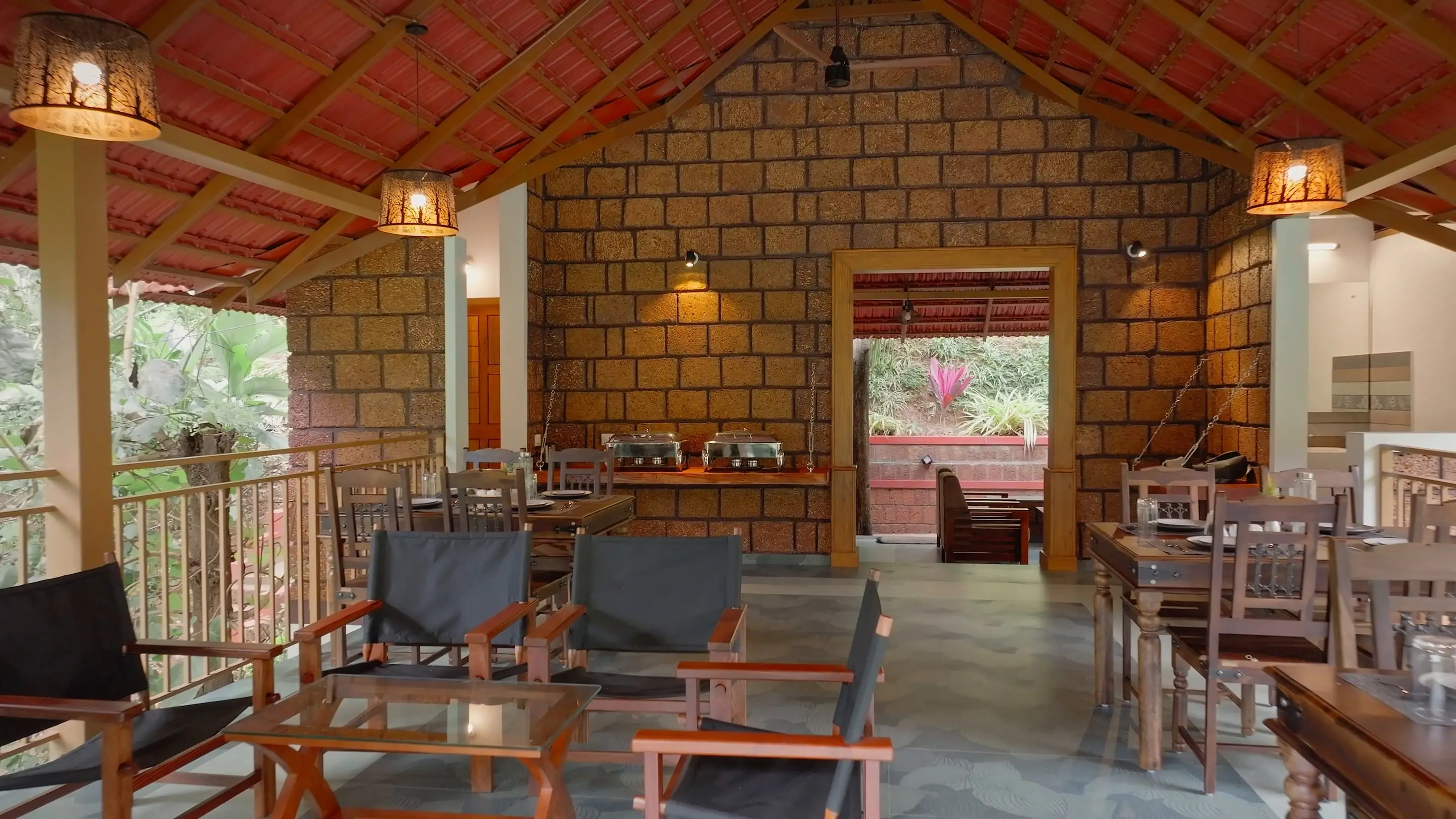The pavilion lounge: laterite walls, lantern light and timber chairs, the dining tables beyond