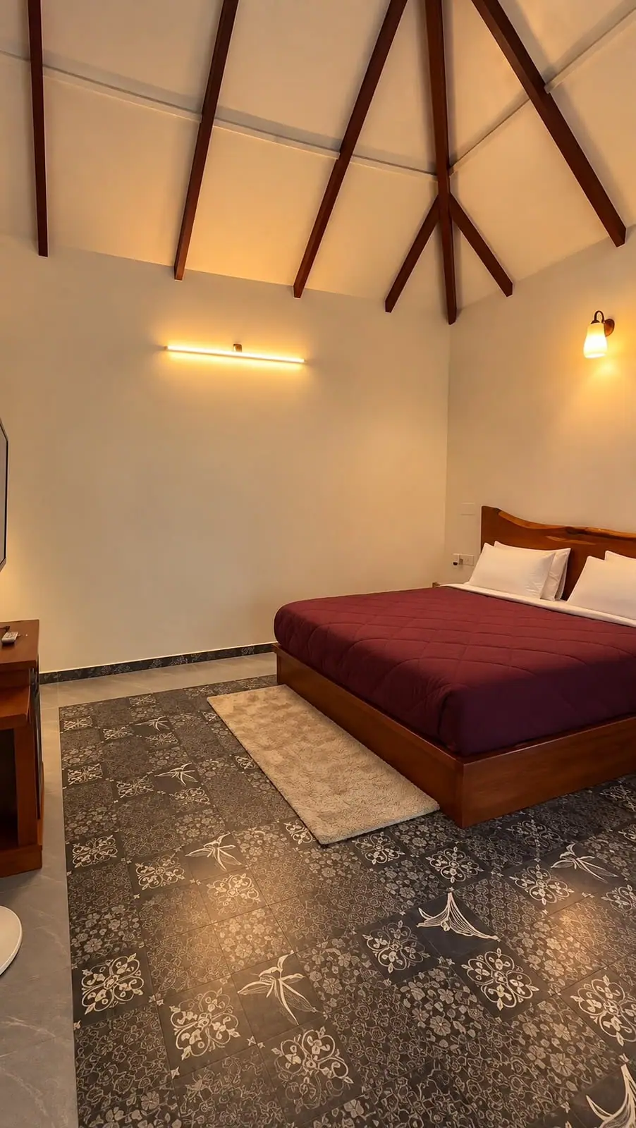 A king bed with a deep red cover against bright white walls