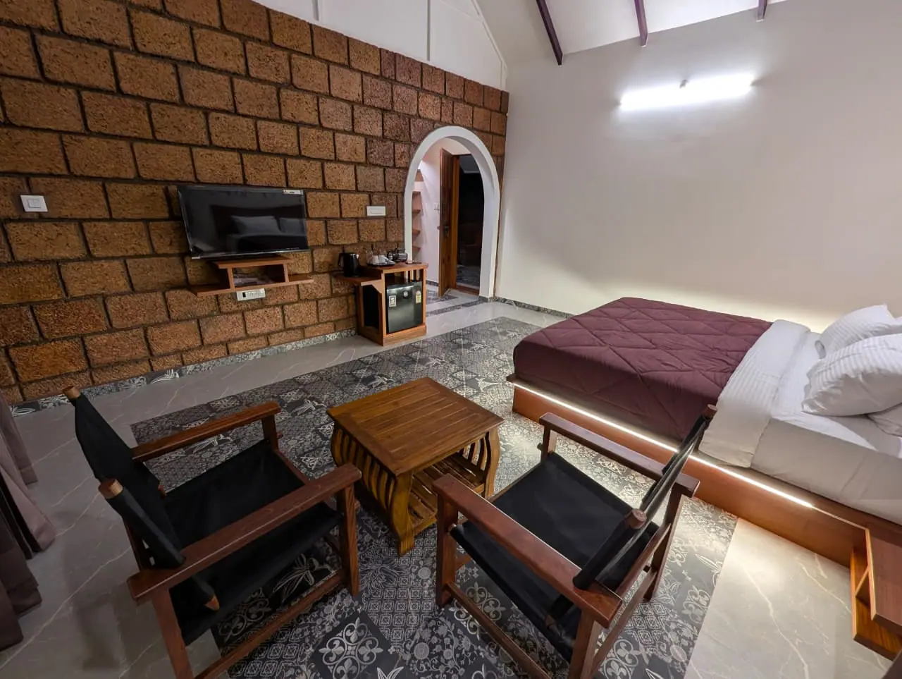 A suite with a laterite wall, a bed and two chairs by the window