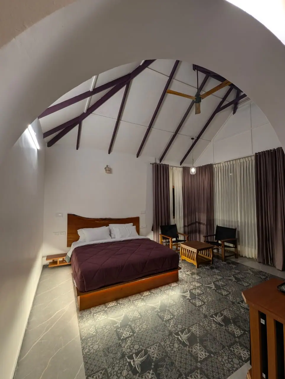 A bedroom with a sloping timber-beamed ceiling