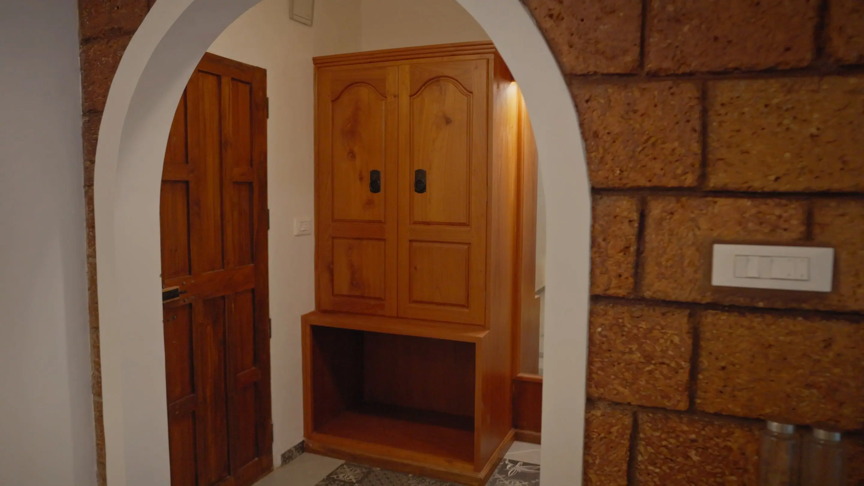 A laterite arch framing the suite's timber wardrobe