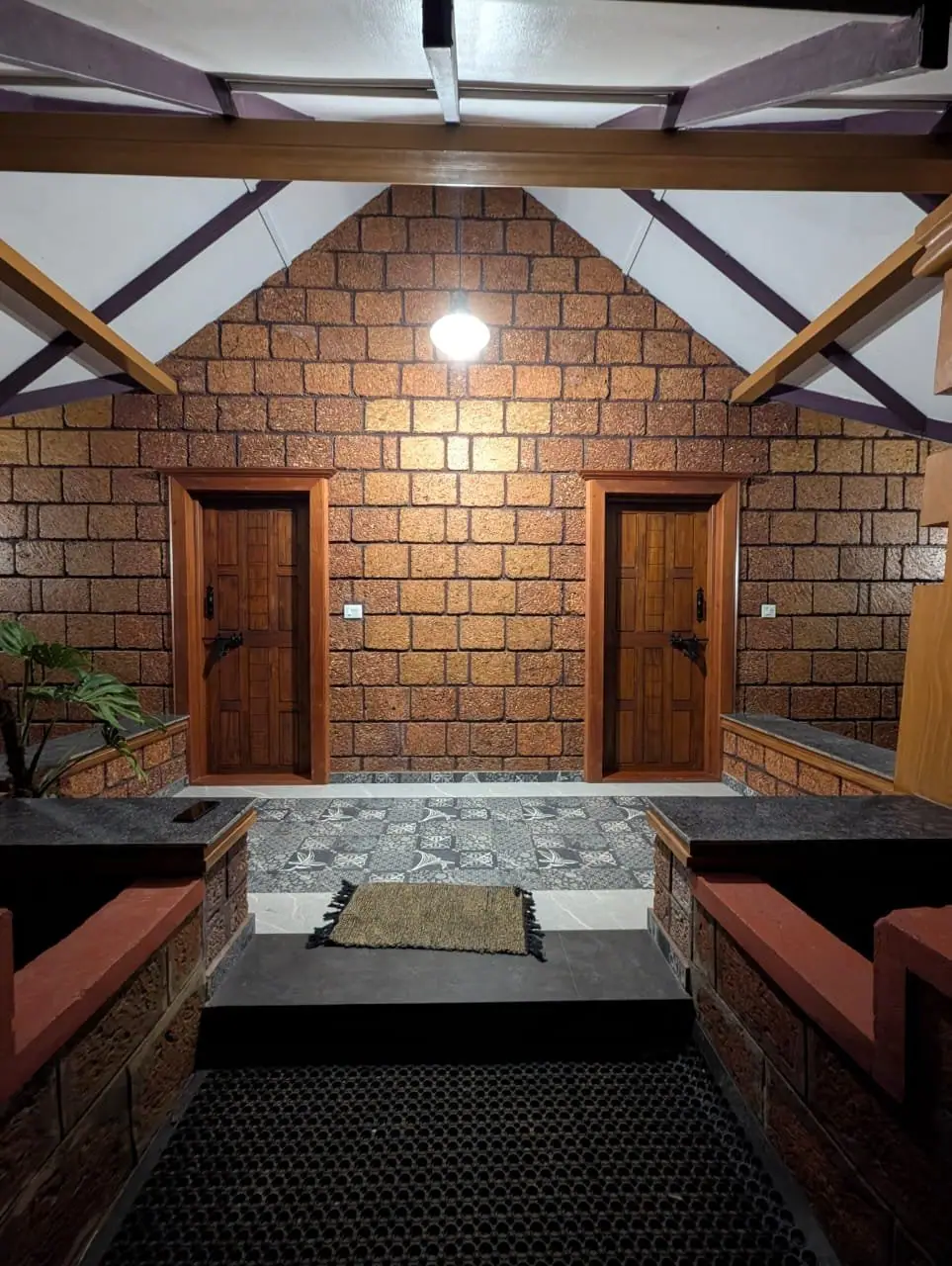 Two timber doors side by side in a laterite wall, under a vaulted roof